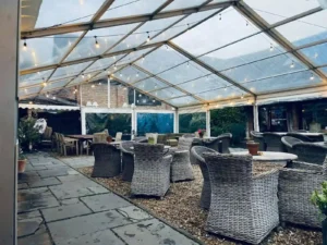 Marquee interior set up with wicker tables and chairs.