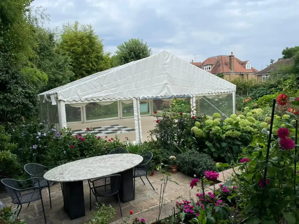 A large marquee for a party set up in garden with lots of lowers.