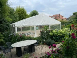 A large marquee for a party set up in garden with lots of lowers.