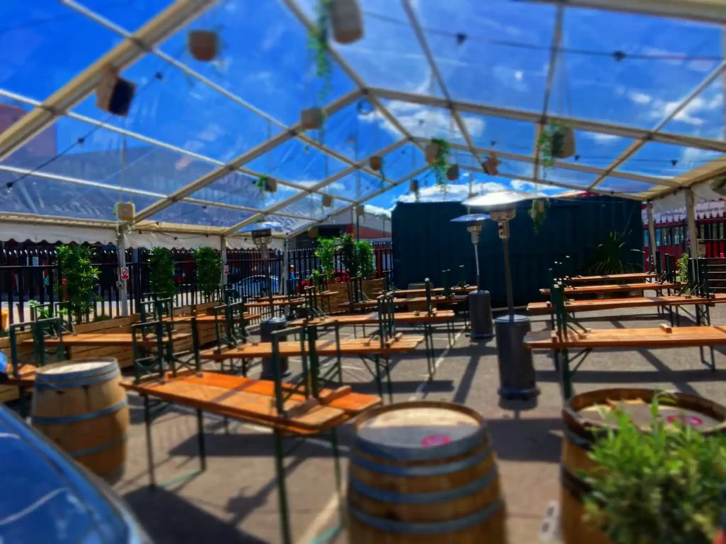 Marquee sheltering an outdoor beer garden with a roof.