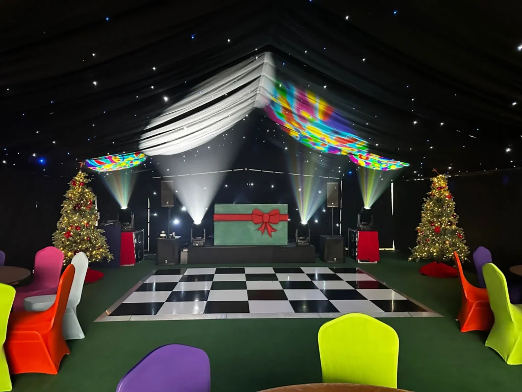 Marquee interior fully decorated with dance floor and props for a corporate party.
