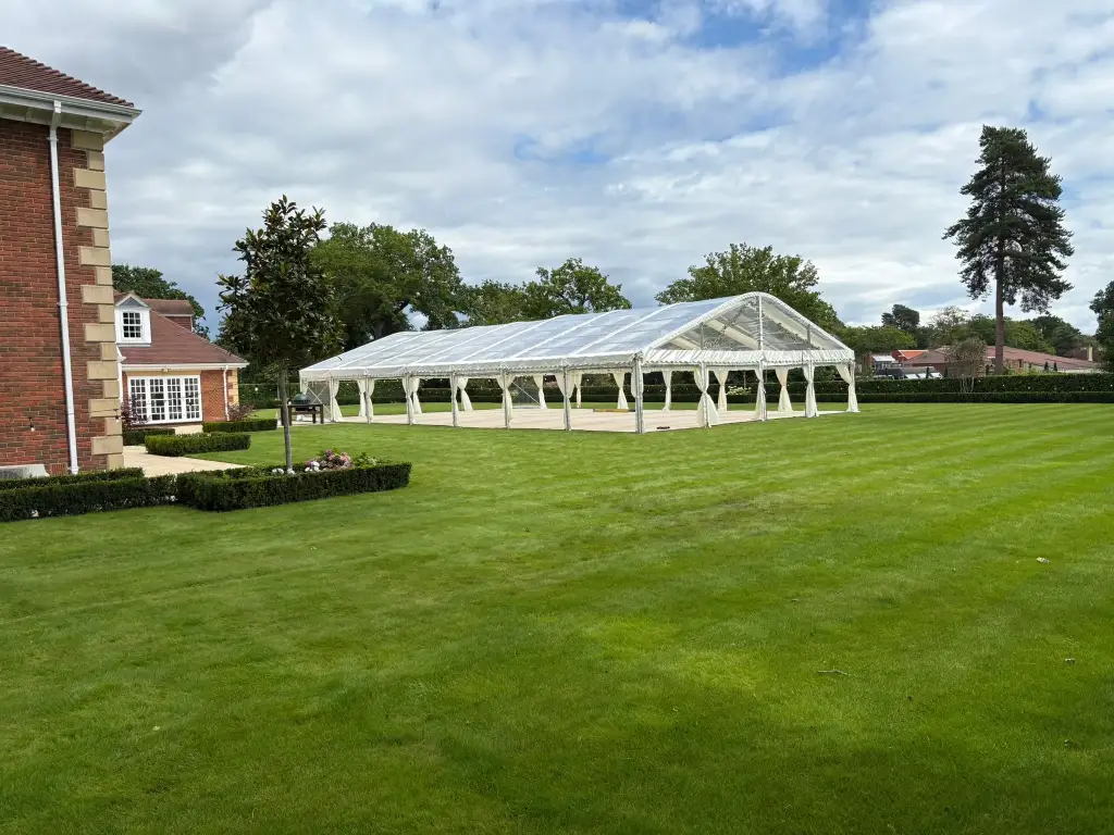Large open-sided marquee set up on lawn outside large building