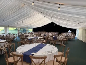Interior of large luxry wedding marquee with navy table runner draped over circle tables