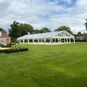 Large open-sided marquee set up on lawn outside large building